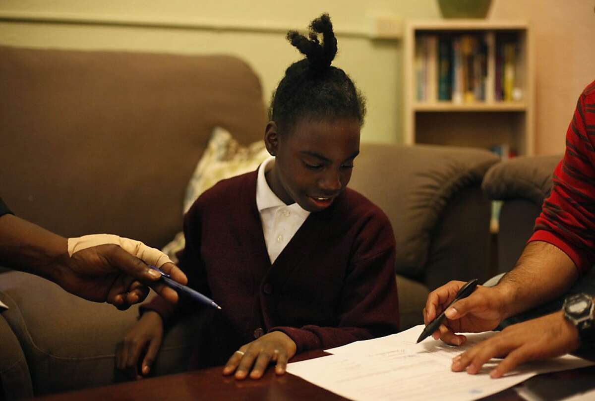 Thomas Bailey (left) and Mauricio Rodriguez, Bilingual Residential Case Manager (right) hand Ashanti Bailey, 10 a pen to sign the Welcome Letter at Raphael House during an intake appointment on Monday, March 18, 2013 in San Francisco, Calif.