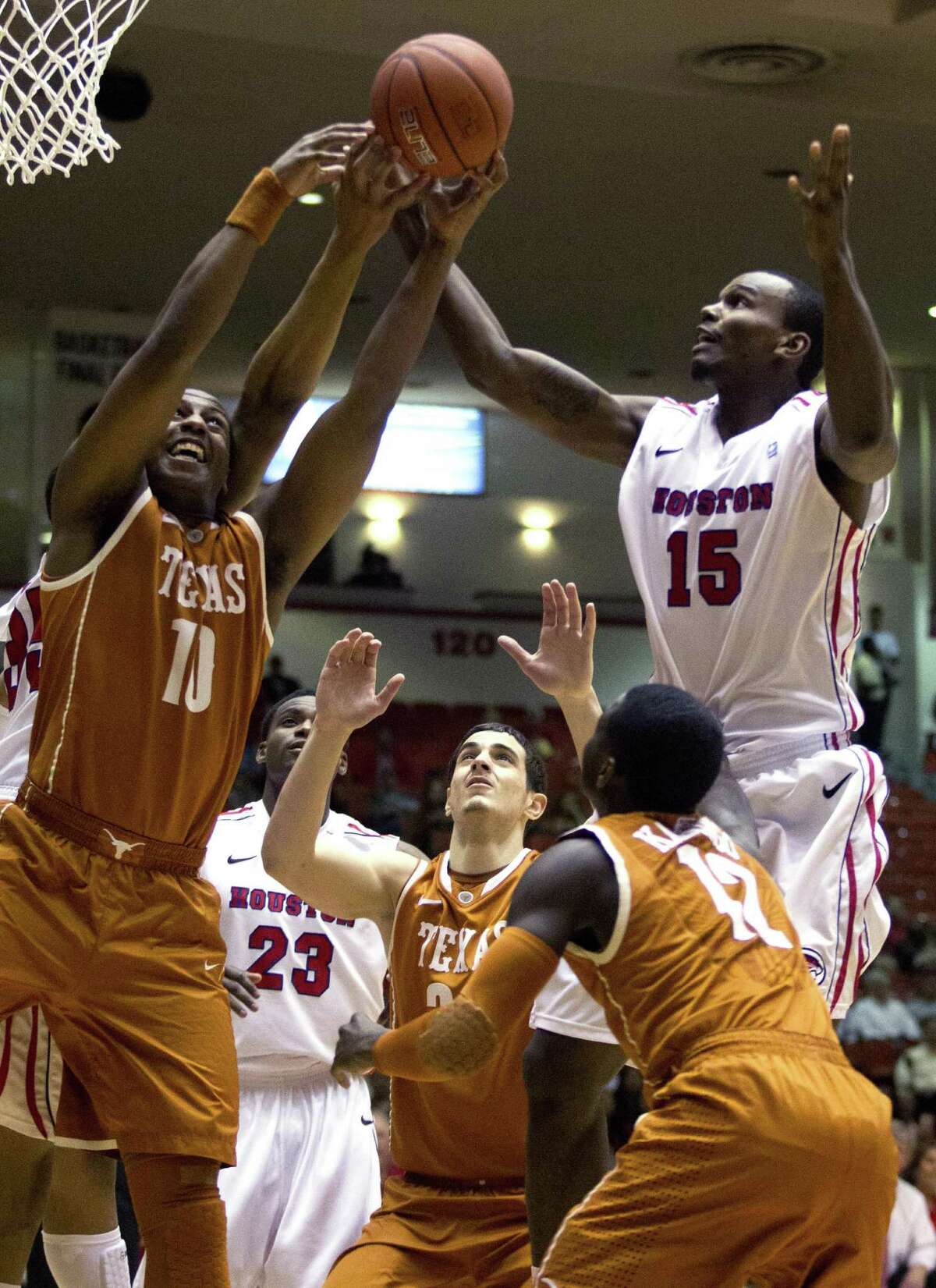 Texas' Jonathan Holmes (left) battles Houston's Leon Gibson (right) and others for a rebound Wednesday night. The Longhorns were knocked out of the CBI with the loss to the Cougars.