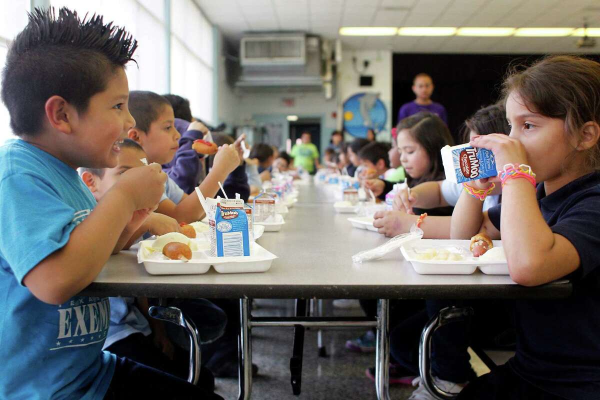 Second-graders Richardo Tellez and Stephanie Riveria, both 8 years old, eat dinner Friday with about 150 schoolmates in the cafeteria at Port Houston Elementary. The program is now spreading to other districts.