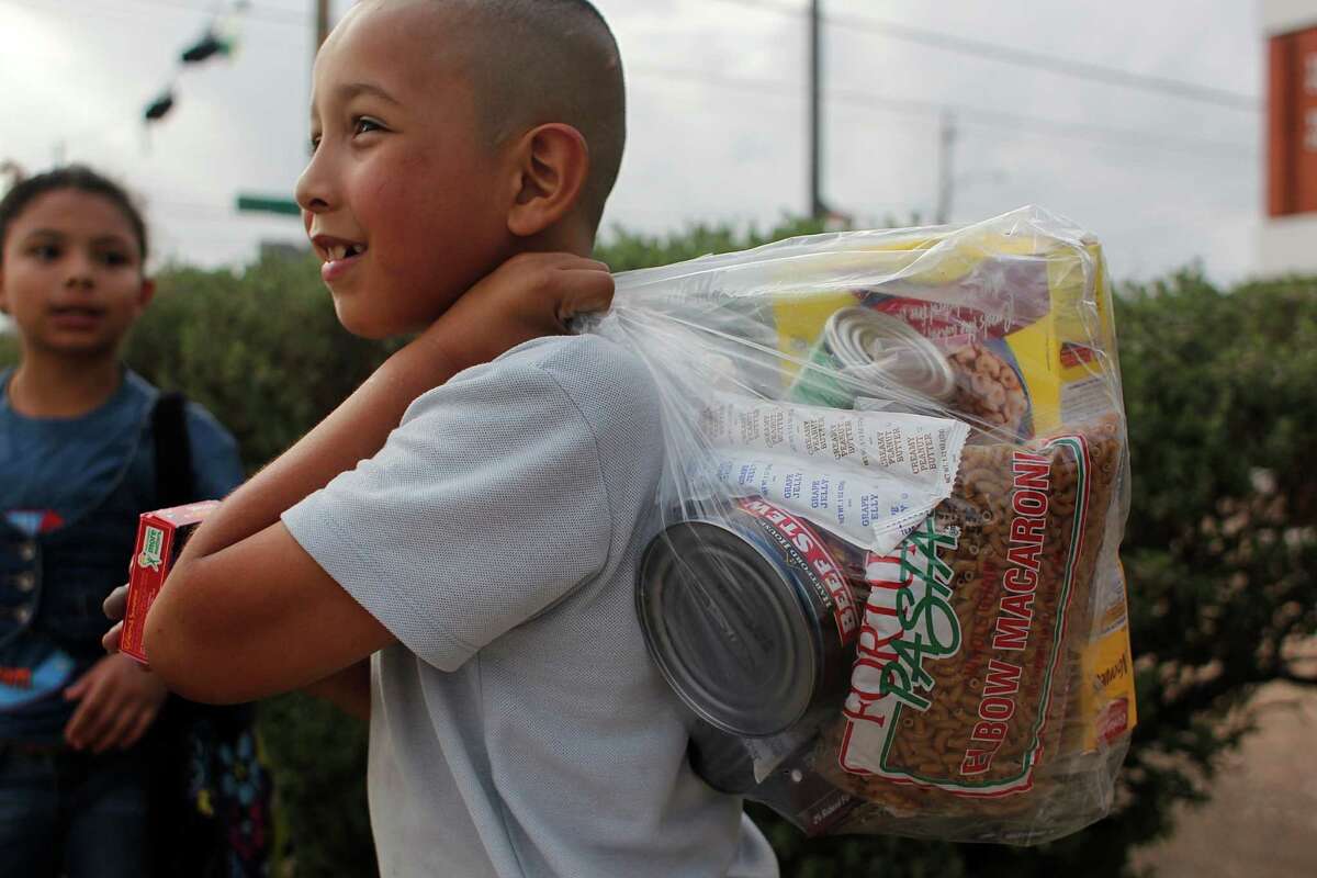 Marvin Hernandez, a student at Port Houston Elementary School, gets ready to take home a bag of food to his family on Friday. The weekend supplies are provided by the Houston Food Bank.