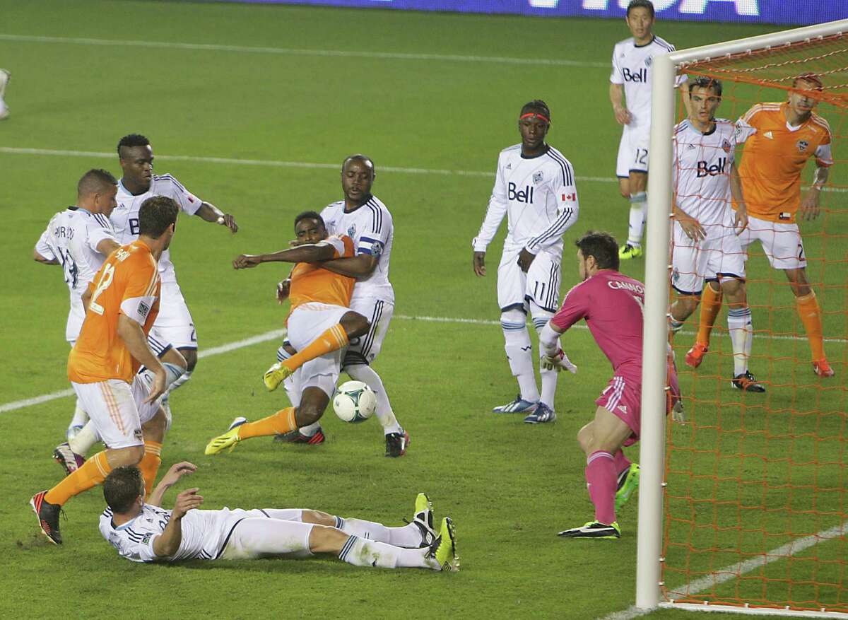 The Dynamo's Warren Creavalle manages to score the winning goal despite being pulled down by the Whitecaps' Nigel Reo-Coker in the penalty area.