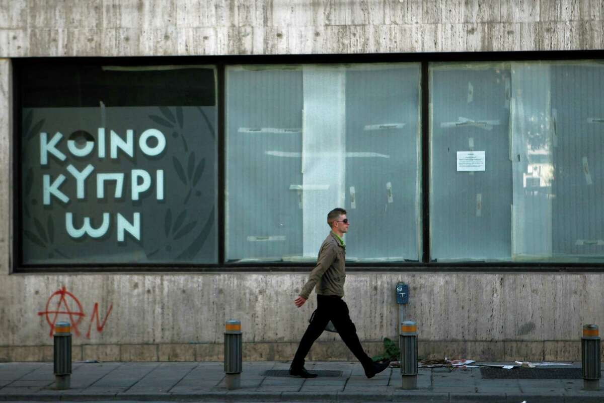 A man passes an empty closed branch of Bank of Cyprus in central capital Nicosia, Cyprus, Sunday, March 24, 2013. A top European official is leading a high-level meeting Sunday afternoon in a last-ditch effort to help Cyprus come up with a plan necessary for a 10 billion euro bailout loan that would save it from bankruptcy. (AP Photo/Petros Karadjias)
