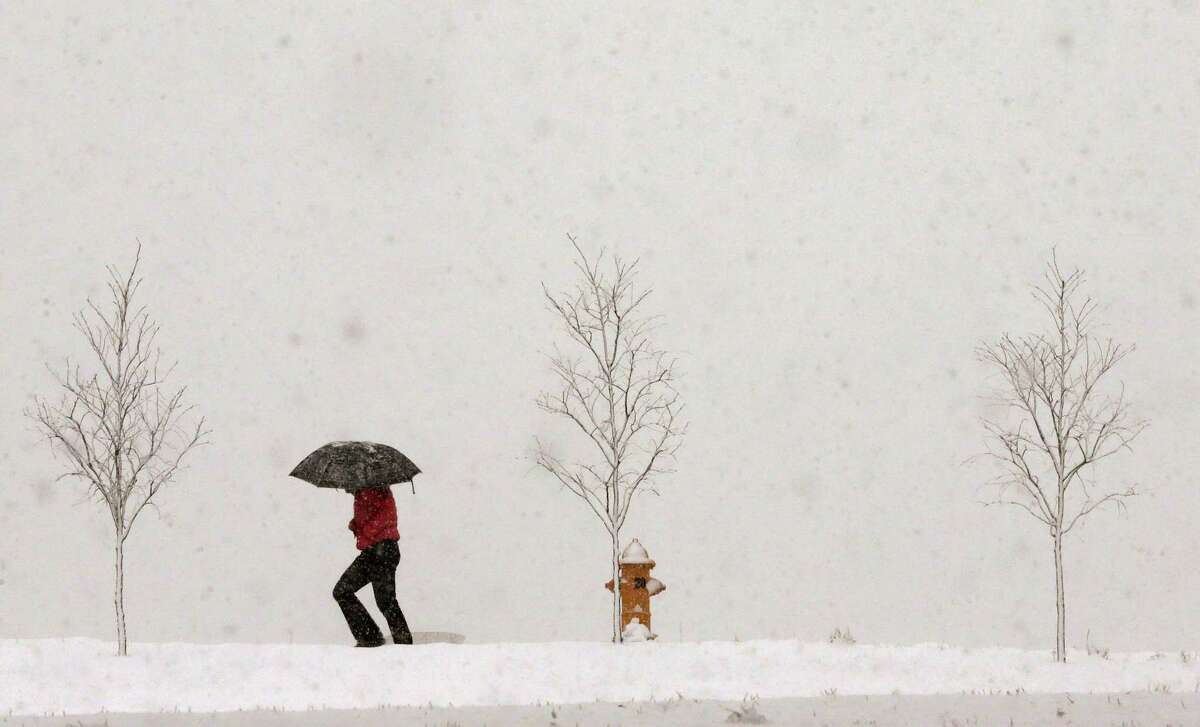 A person walks along Jayhawk Boulevard with an umbrella as snow from a winter storm begins to fall in Lawrence, Kan., Saturday, March 23, 2013. (AP Photo/Orlin Wagner)