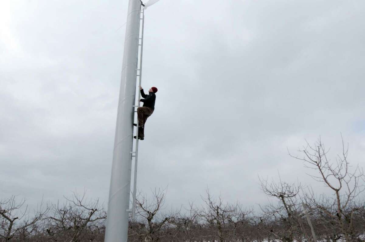 Derek Grout, marketing manager for Golden Harvest Farms climbs up one of the orchard fans on Wednesday, March 20, 2013 in Valatie, NY. The orchard has installed six orchard fan systems to help keep the trees from being damaged during the flowering season because of cold temperatures. Each fan can circulate air for about 15 acres. The fans will only be effective if there is a temperature inversion. (Paul Buckowski / Times Union)