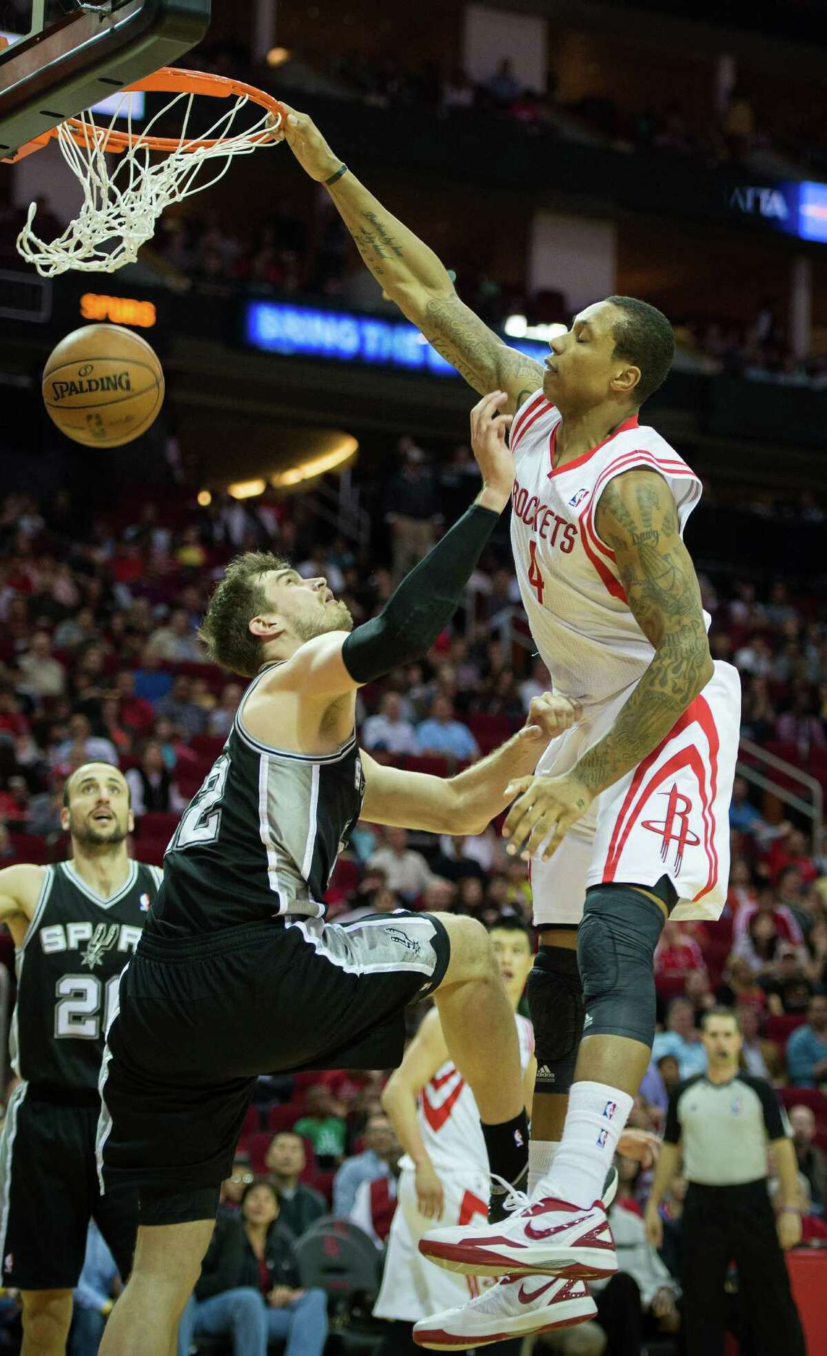 The Rockets' Greg Smith (4) puts the power in power forward, dunking over Spurs center Tiago Splitter (22) during the second half of Sunday night's game at Toyota Center.