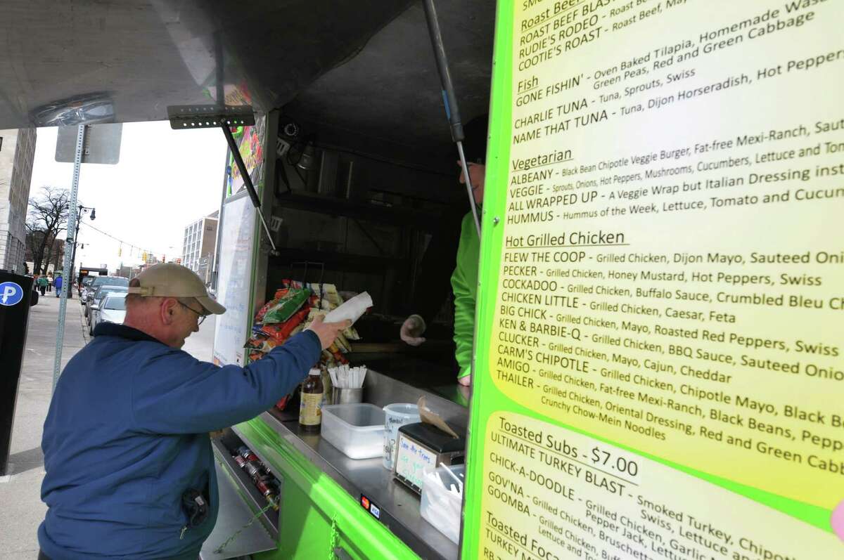 Customer Bill Waller from Clifton Park grabs his lunch at the Healthy Cafe food truck outside the Capitol on Washington Ave. on Monday, March 25, 2013, in Albany, NY. Monday was the first day this season that the food carts and trucks were allowed back at the curb. Kim Comtois, manager of the Healthy Cafe, said that this season they hope to use the smartphone app GrubHub to allow customers to order food in the area around the Capitol and the Healthy Cafe will deliver. (Paul Buckowski / Times Union)