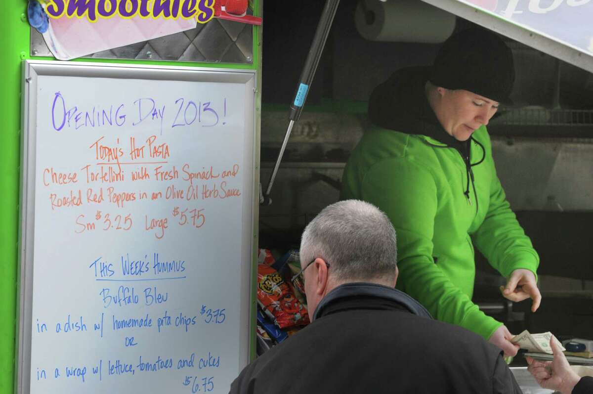 Manager Kim Comtois hands change back to a customer at the Healthy Cafe food truck outside the Capitol on Washington Ave. on Monday, March 25, 2013, in Albany, NY. Monday was the first day this season that the food carts and trucks were allowed back at the curb. Kim Comtois, manager of the Healthy Cafe, said that this season they hope to use the smartphone app GrubHub to allow customers to order food in the area around the Capitol and the Healthy Cafe will deliver. (Paul Buckowski / Times Union)