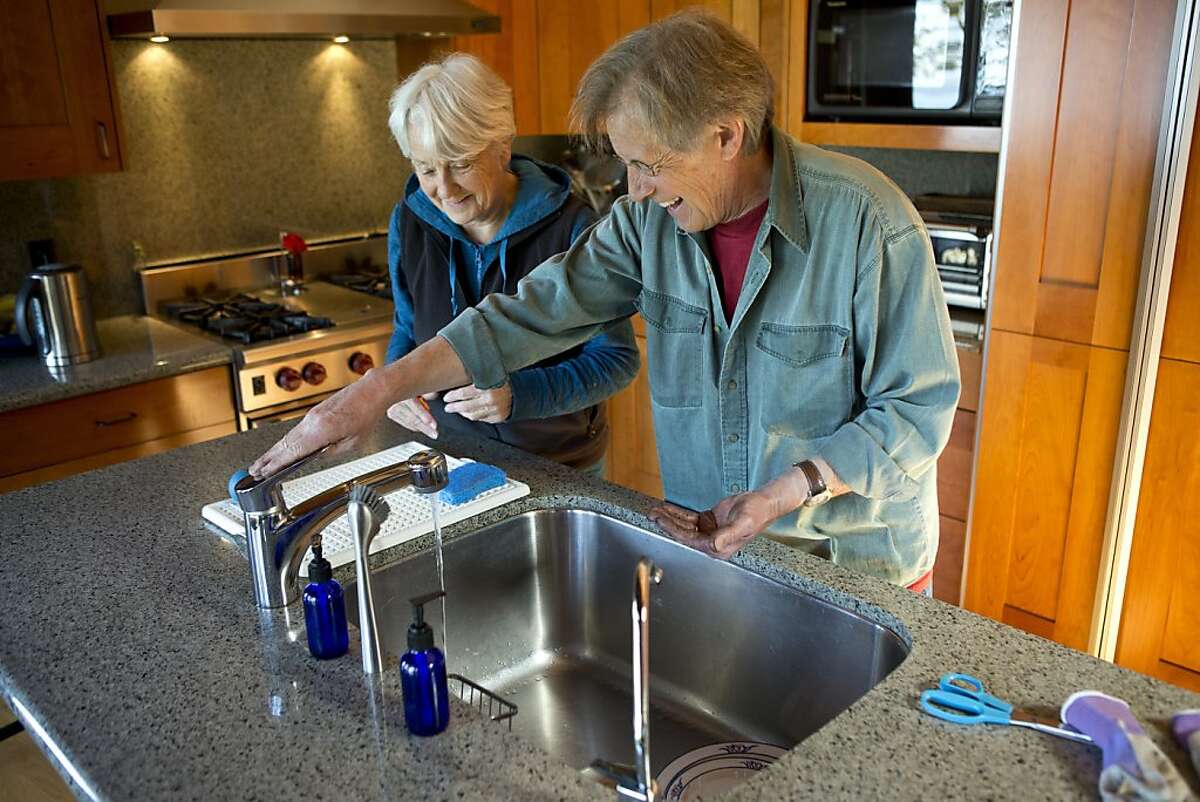 Ashby Village volunteer Angus Dunstan (right) washes his hands with Barbara Blomer after helping her plant flowers in her backyard on Thursday, March 21, 2013 in Berkeley, Calif.