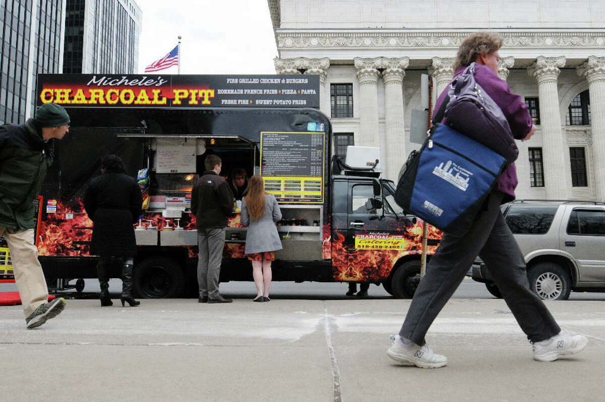 Customers line up for lunch at Michele's Charcoal Pit food truck outside the Capitol on Washington Ave. on Monday, March 25, 2013 in Albany, NY. Monday was the first day this season that the food carts and trucks could be back at the curb. Michele's Charcoal Pit has been around since 1986 and workers said that almost all their prices have stayed the same from last season. (Paul Buckowski / Times Union)