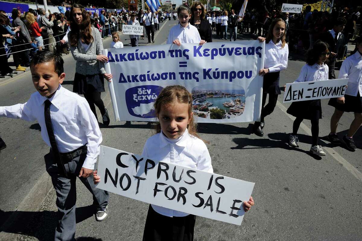 Students hold placards the ones on the right reads in Greek "we don't sell out "during a parade for Greek independence day celebrations at the southern port city of Limassol, Cyprus,Monday, March 25, 2013. Cyprus secured what its politicians described as a ?“painful?” solution to avert imminent bankruptcy, agreeing early Monday to slash its oversize banking sector and make large account holders take losses to help pay to secure a last-minute euro10 billion (US$13 billion) bailout. (AP Photo/Pavlos Vrionides)