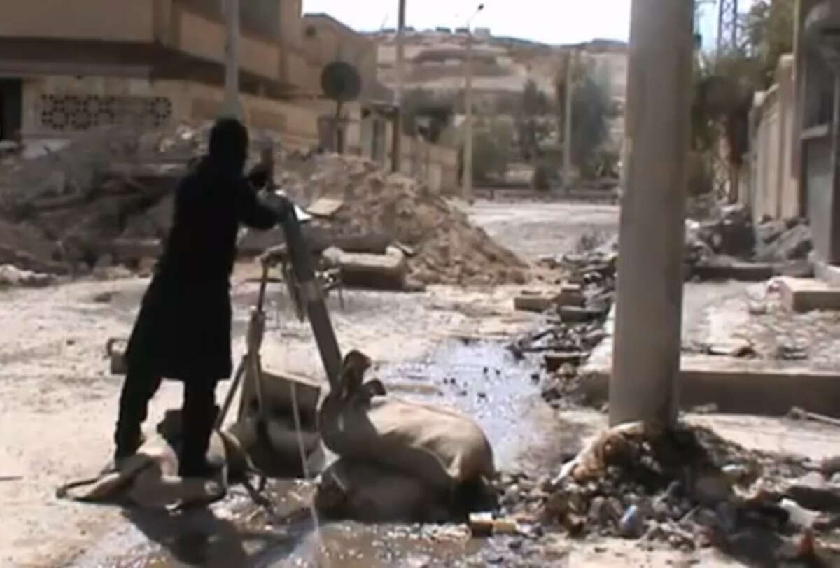 In this Sunday, March 24, 2013 image taken from video obtained from the Ugarit News, which has been authenticated based on its contents and other AP reporting, Free Syrian Army fighters drops a shell into a firing tube, in Damascus countryside, Syria. (AP Photo/Ugarit News via AP video)