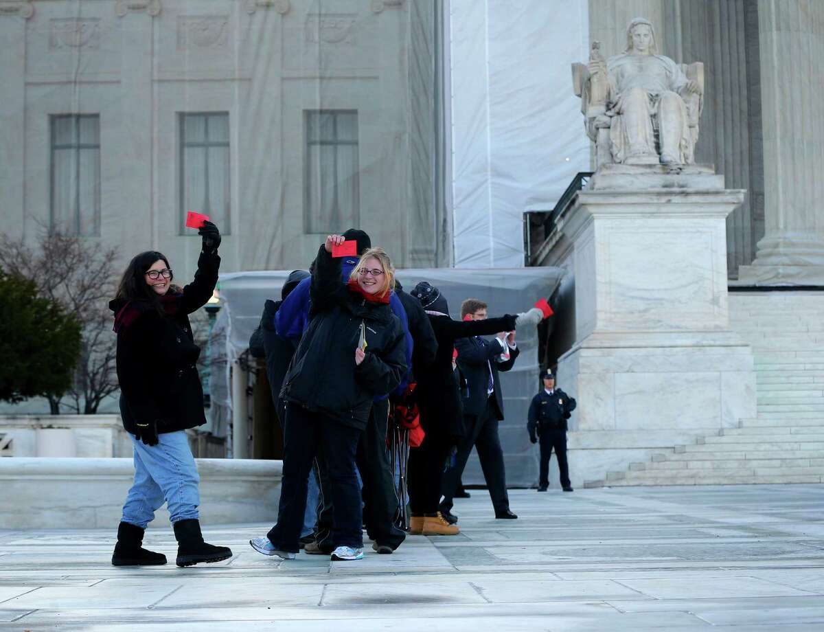 People hold up their tickets that had been issued to the general public for entrance Supreme Court in Washington, Tuesday, March 26, 2013, for the court's hearing on California’s voter approved ban on same-sex marriage. Some people waited in line _ even through light snow _ since Thursday for the coveted seats for the argument over California's Proposition 8.