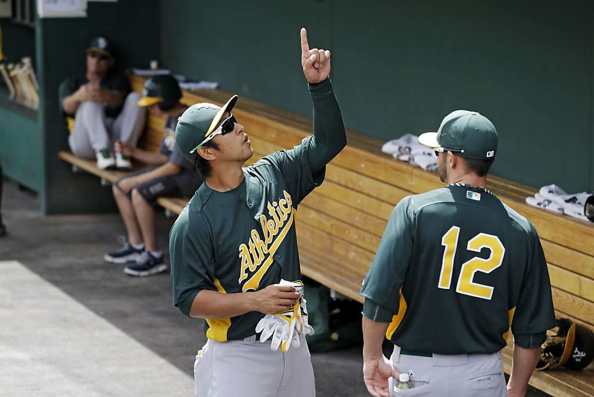 Oakland Athletics' Hiroyuki Nakajima points out something to Andy Parrino (12) before an exhibition spring training baseball game against the Cleveland Indians Tuesday, March 26, 2013, in Goodyear, Ariz. (AP Photo/Mark Duncan)