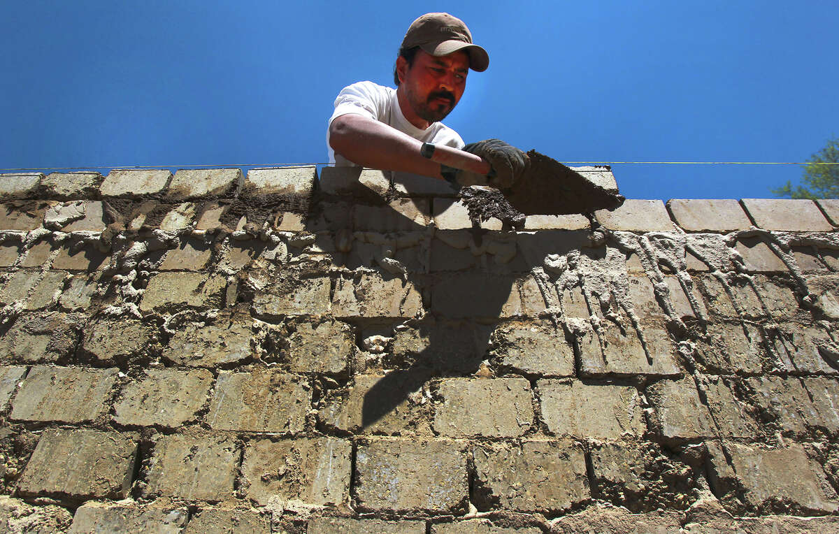 Isidro Hernandez lays compressed earth blocks on a wall of an apartment building on Eisenhauer Road. Urban Earth is building apartments designed by Lake|Flato with compressed earth block.