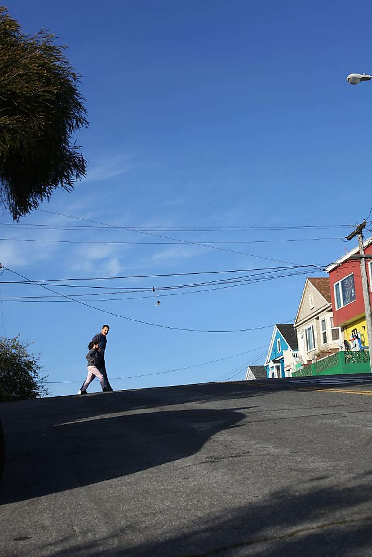 Two pedestrians cross Paris Street heading up the Excelsior Heights hill on March 24, 2013 in San Francisco, Calif.