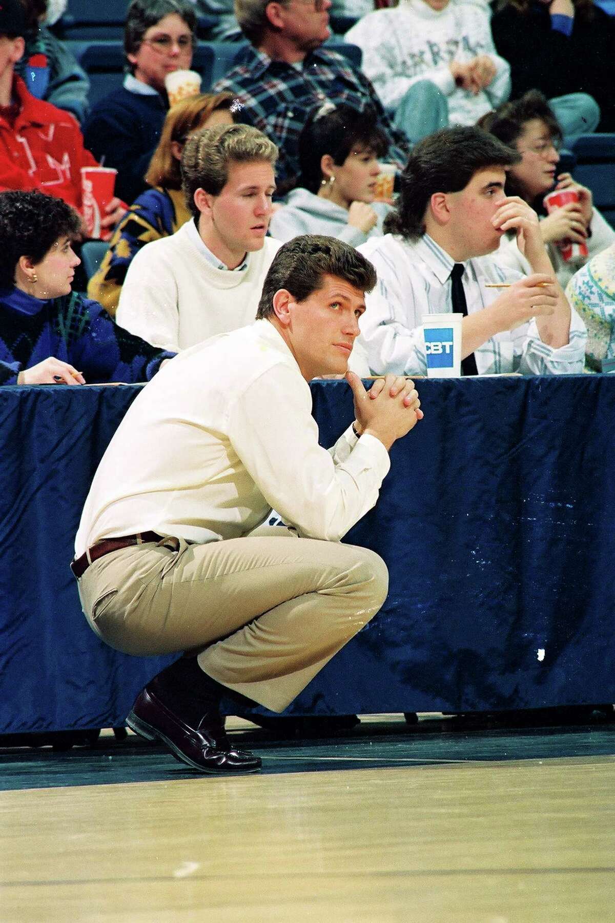 University of Connecticut coach Geno Auriemma watches the action, while crouched on the sideline, Gampel Pavilion, Storrs, CT, 1991. (Photo by Bob Stowell/Gety Images)