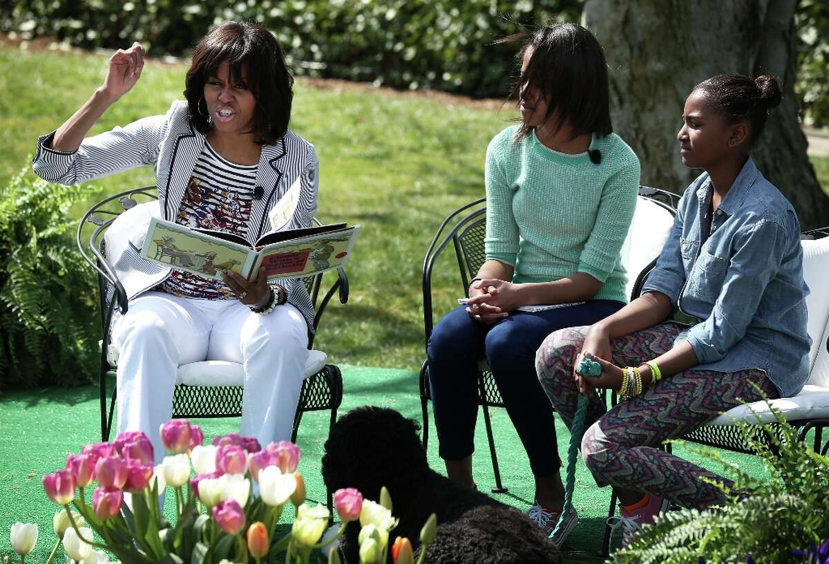 WASHINGTON, DC - APRIL 01: (AFP OUT) U.S. first lady Michelle Obama (L) reads the story Cloudy with a Chance of Meatballs to children as daughters Sasha (R) and Malia (2nd L) look on during the annual White House Easter Egg Roll on the South Lawn of the White House April 1, 2013 in Washington, DC. President Barack Obama and first lady Michelle Obama hosted thousands of people during the annual celebration of Easter.