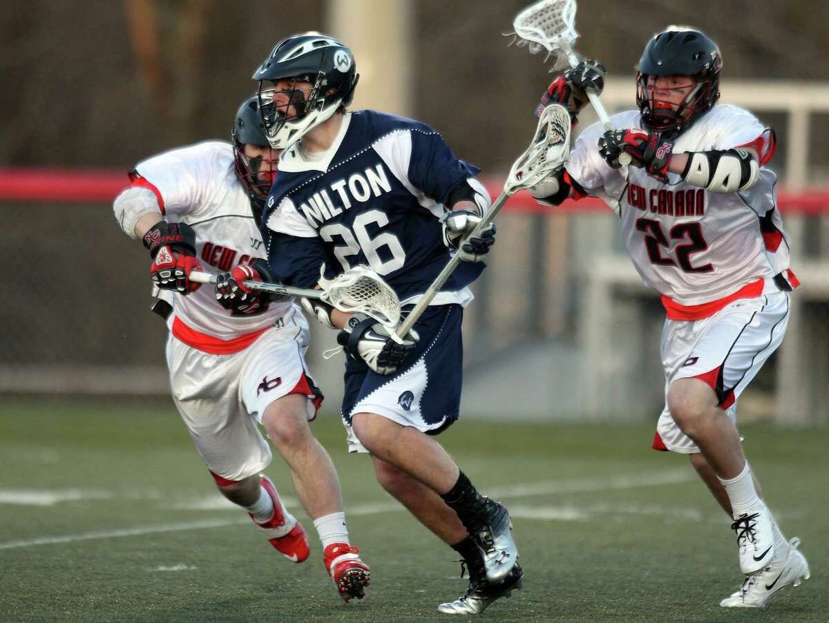 Wilton senior middie Thomas Hayes runs by a pair of New Canaan defenders during first half FCIAC action in New Canaan. © J. Gregory Raymond for The Advocate