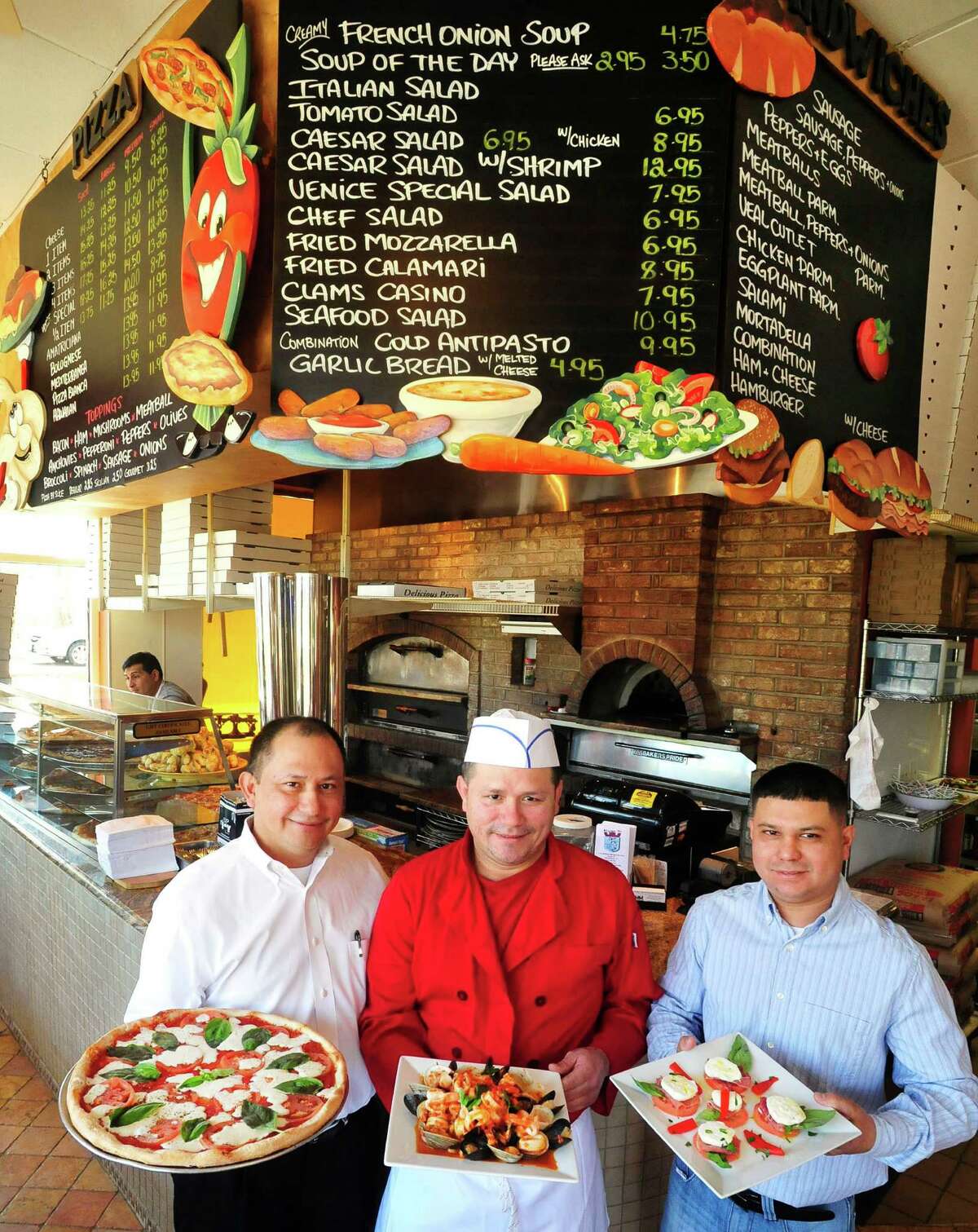 Left to right are Joey Escobar, with a Margherita Pizza; German Escobar, with Zuppa de Pesce; and Jose Caballero, with fresh mozzarella caprese. All three are owners of Venice Restaurant & Pizza, in Ridgefield, Conn. Wednesday, April 3, 2013.