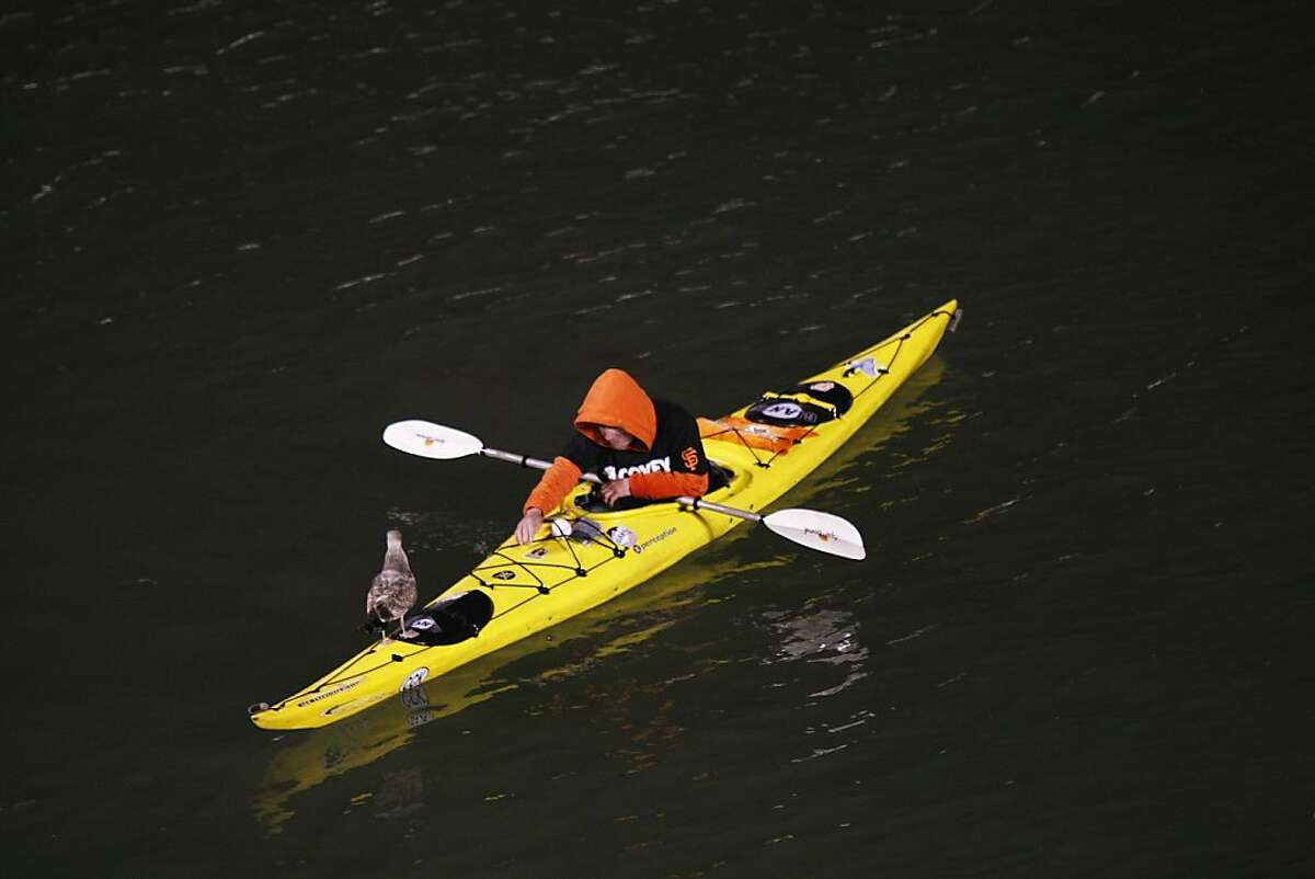 A lone kayaker attemps to feed a seagull as he waits for baseballs to fly into the bay on Friday, March 29th. Seagulls gather after baseball games at AT&T Park to eat leftover food.
