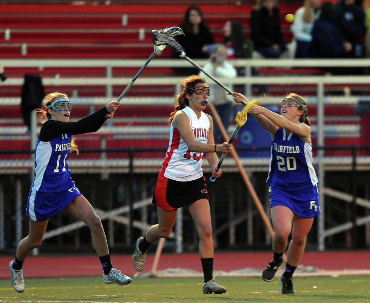 Fairfield Warde's Kelly Powlishen, center, passes the ball as she is pressured by Fairfield Ludlowe's #11 KC McAuliffe, left, and #20 Brittany Rosenfeld, during girls lacrosse action in Fairfield, Conn. on Friday April 5, 2013.