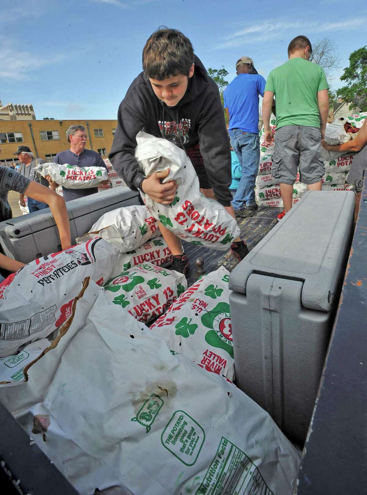 Anthony Wimmer, center, and other church members, load 50 lb. bags of potatoes into the back of a pickup truck that needed several pounds worth. Members of five Orange Churches hosted the second "Sharefest of Orange" at the First United Methodist Church of Orange Saturday morning. They gathered for what they called the 2013 Potato Drop where they distributed 42,000 pounds of potatos to families and groups who needed them. Distribution started at 9 a.m. and lasted till there were no more potatos. Dave Ryan/The Enterprise