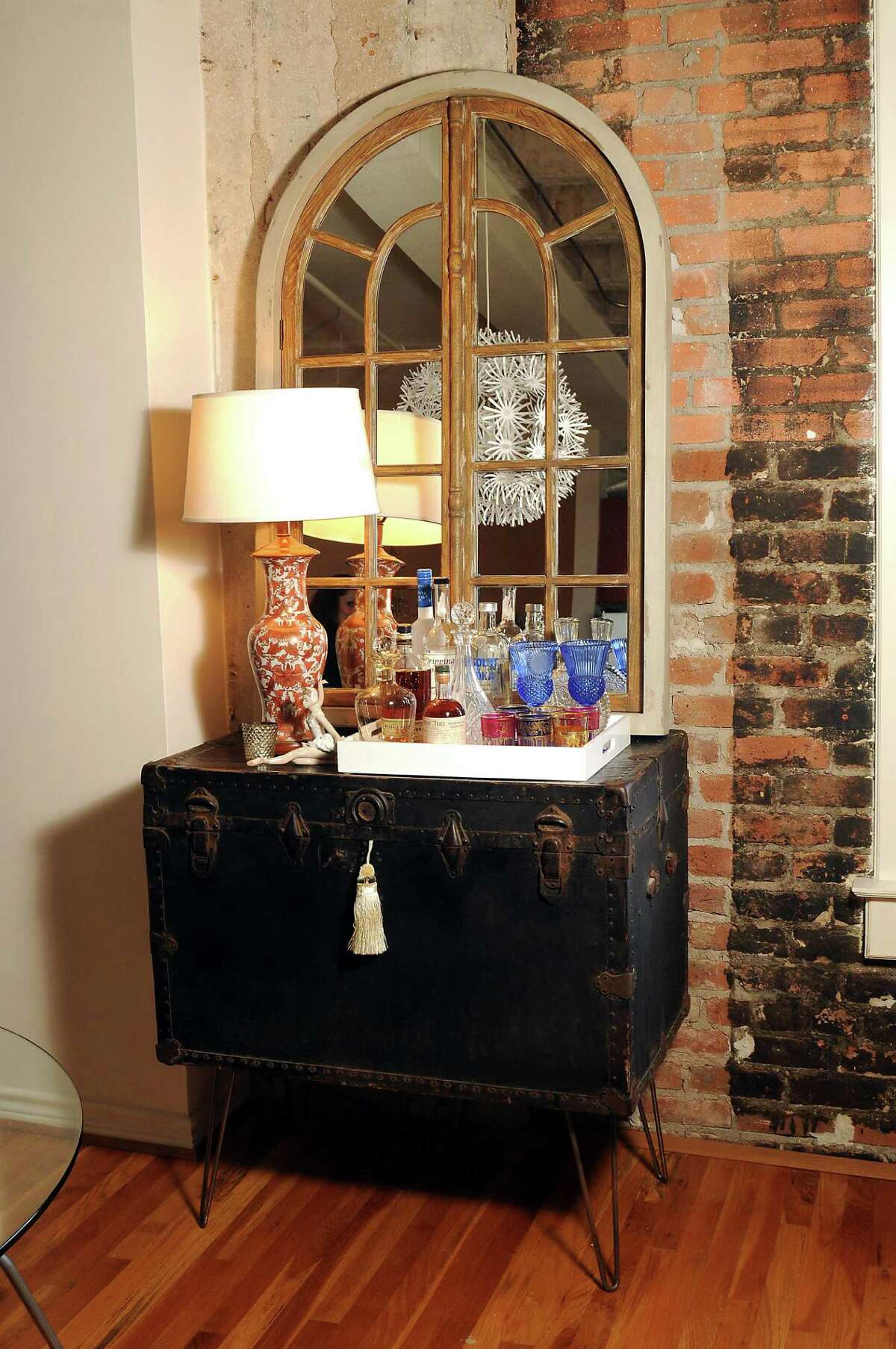 Clockwise from top: Lindsey Brown in her downtown loft. A modern dining table and Ikea chairs offset antiques peppered about the space and the apartment's historic bones. A 100-year-old steamer trunk found on Craigslist serves as a bar. A statue of dancers in the living room, purchased at the Houston Ballet Ball auction, nods to Brown's love of dance.