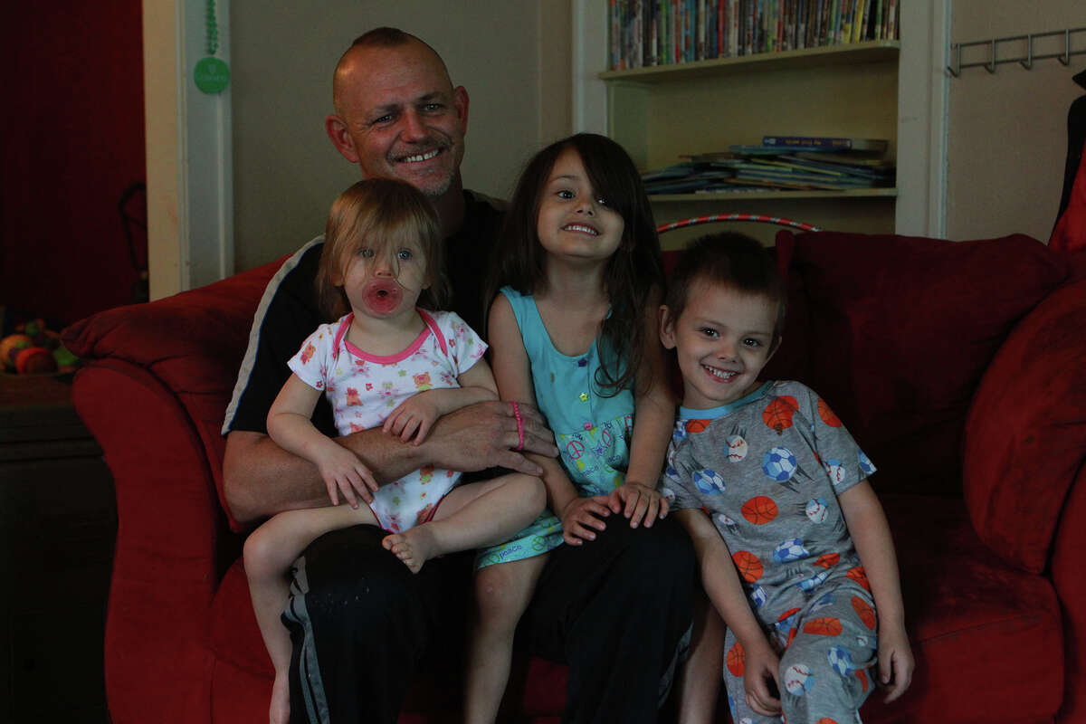 Shad Christopher Modesett sits with his children, Aolani, 1 (from left); Emily, 4; and Dorian, also 4, at the family’s San Antonio home. In February 2012, he was involved in a texting-while-driving wreck that severely injured Police Officer Jonathan Esquivel.
