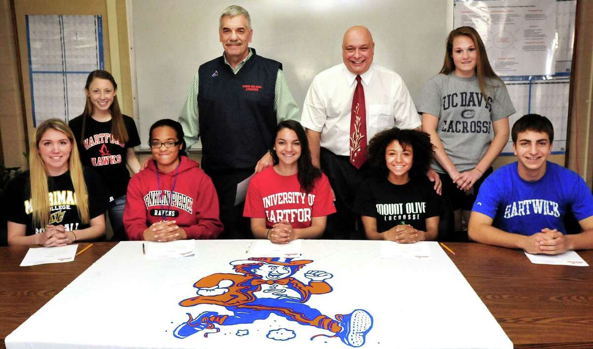 Student athletes and administrators pose for parents during the Danbury High School Athletic Department signing ceremony, in Danbury, Conn. Thursday, April 11, 2013. From left are Kara Orr, Kristen Dakin, Melanie Hill, athletic director Chip Salvestrini, Marisa Ferguson, school principal Gary Bocaccio, Raven Winters, Pauline Kaplan and Kenny Wilson.