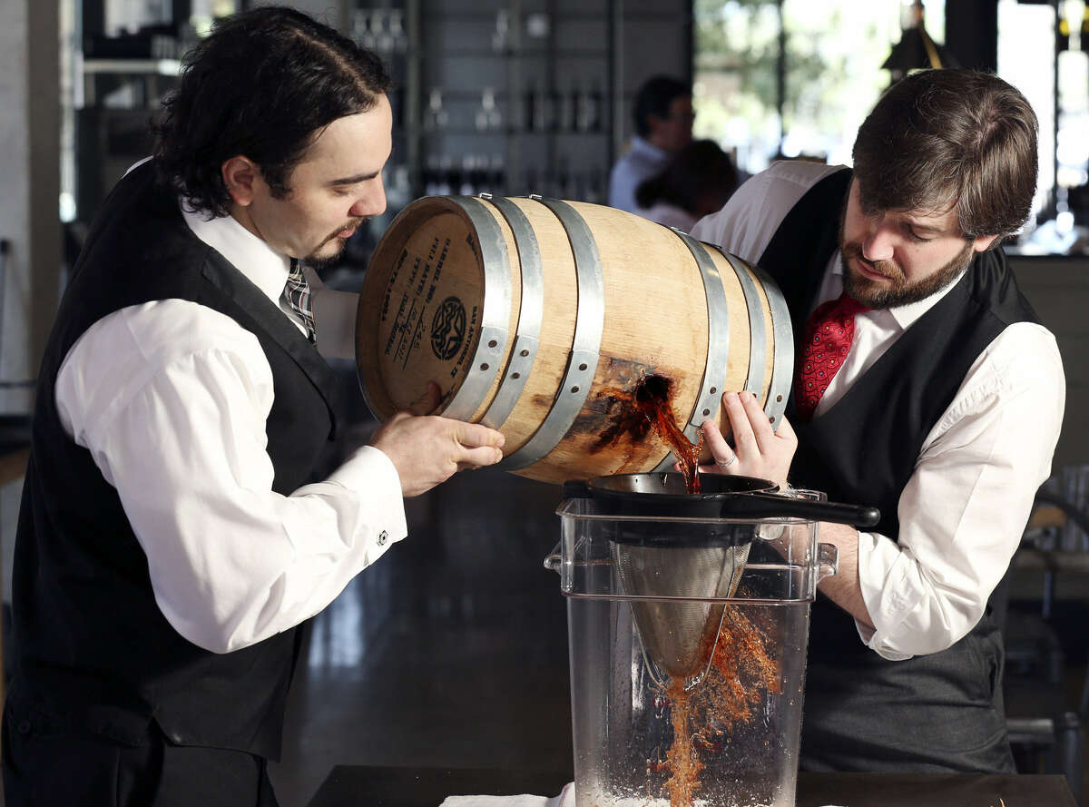 Arcade Midtown Kitchen bartender Matthew Sandoval (left) and bar manager Christopher Ware filter cocktail ingredients from a 5-gallon barrel for the Vieux Carre cocktail.