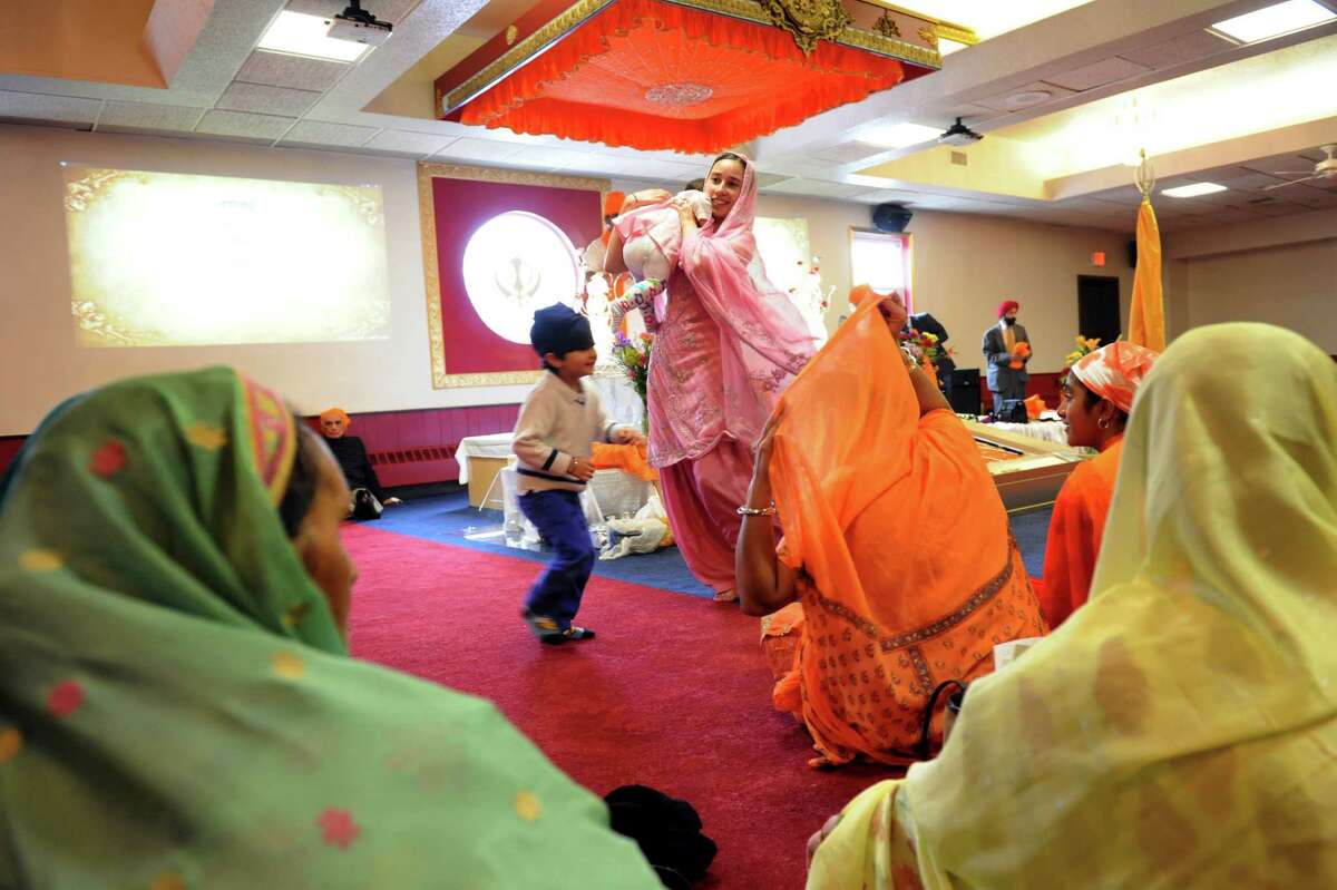Ramandeep Kaur of Clifton Park, center, collects her daughter, Eknoor Sandhu, 11 months, during the inaugural services of a new Sikh temple on Saturday, April 13, 2013, at Capital Gurudwara in Rensselaer, N.Y. (Cindy Schultz / Times Union)