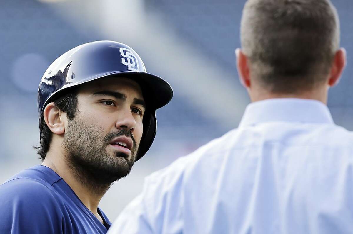 FILE - In this April 12, 2013, file photo, San Diego Padres' Carlos Quentin, left, talks with general manager Josh Byrnes during warmups before a baseball game against the Colorado Rockies in San Diego. Quentin on Sunday, April 14, dropped his appeal and began serving an eight-game suspension for rushing the mound and inciting a brawl in which Los Angeles Dodgers pitcher Zack Greinke broke his left collarbone. (AP Photo/Lenny Ignelzi, File)