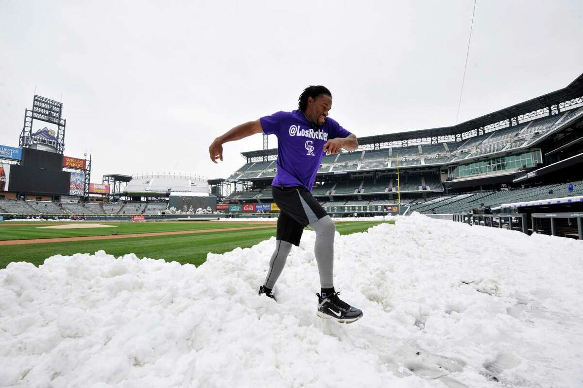 Colorado Rockies' Eric Young Jr. jumps over a pile of snow before the start of a baseball doubleheader between the New York Mets and the Rockies on Tuesday, April 16, 2013, in Denver. (AP Photo/Jack Dempsey)
