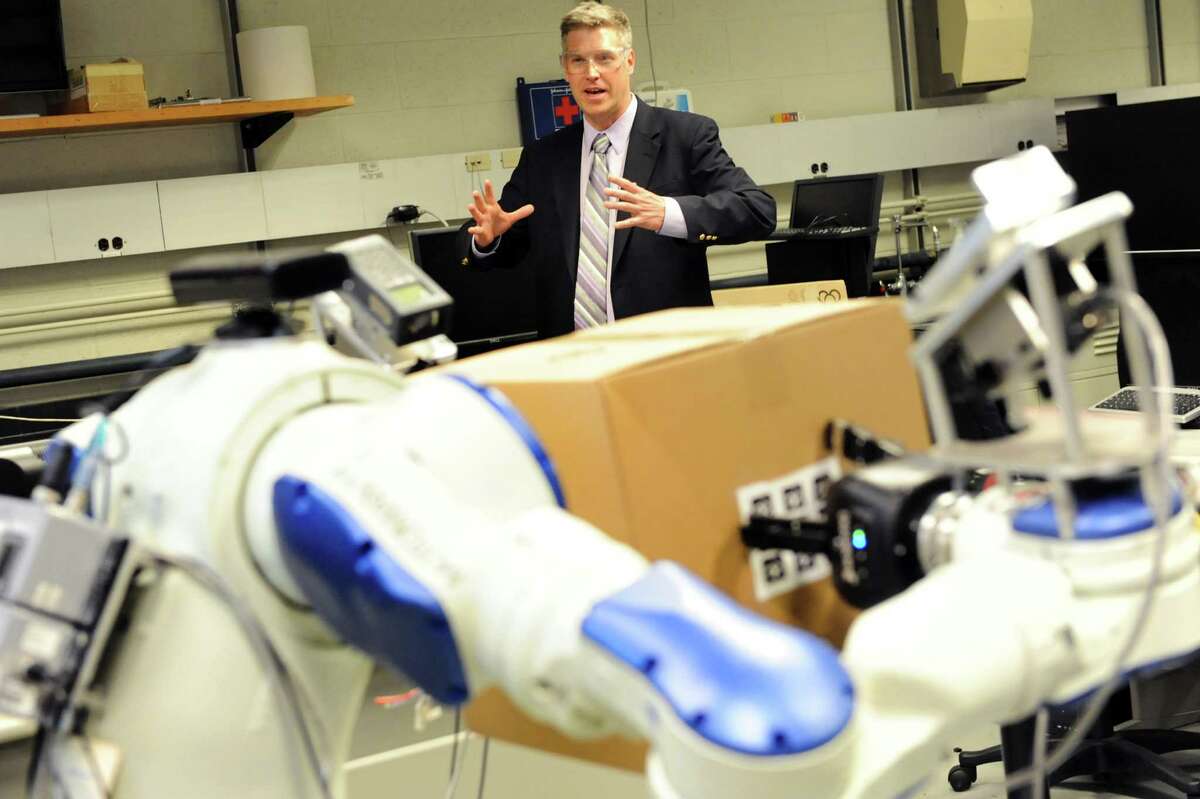 Patrick D. Gallagher, U.S. Under Secretary of Commerce for Standards and Technology, uses arm movements to direct a robot, in the foreground, during a tour on Tuesday, April 16, 2013, at Rensselaer Polytechnic Institute in Troy, N.Y. (Cindy Schultz / Times Union)