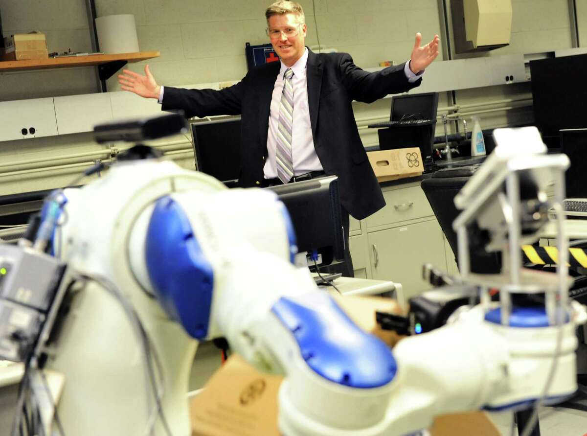 Patrick D. Gallagher, U.S. Under Secretary of Commerce for Standards and Technology, opens his arms as he directs a robot, in the foreground, to drop a box during a tour on Tuesday, April 16, 2013, at Rensselaer Polytechnic Institute in Troy, N.Y. (Cindy Schultz / Times Union)