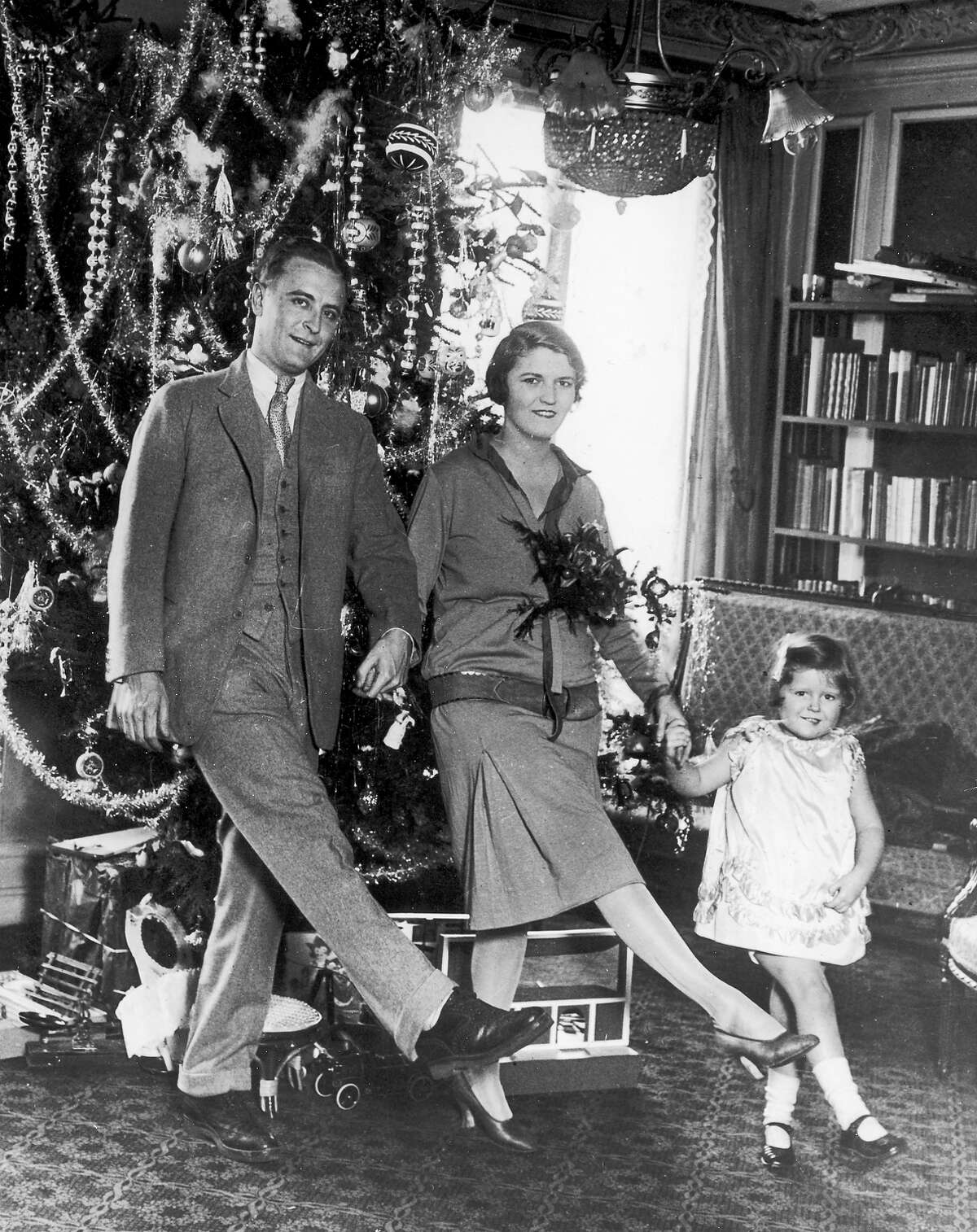 American author F Scott Fitzgerald dances with his wife Zelda Fitzgerald and daughter Frances in front of the Christmas tree in Paris.