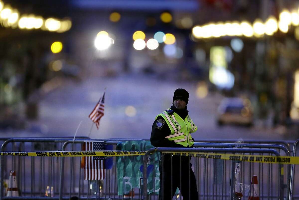 A police officer walks along a barricade on Boylston Street near the finish line of Monday's Boston Marathon explosions, which killed at least three and injured more than 140, Thursday, April 18, 2013, in Boston. (AP Photo/Matt Rourke)