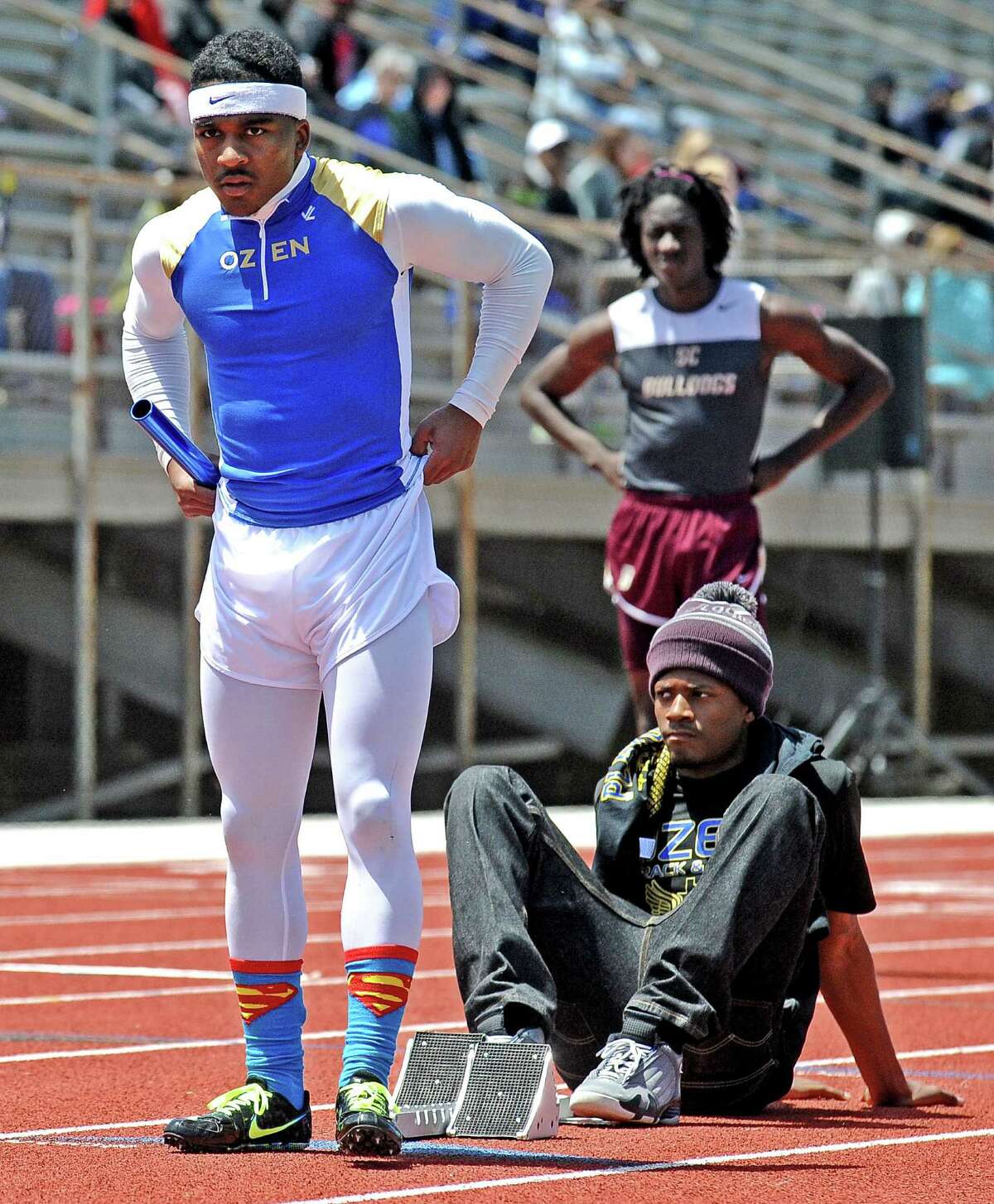 Ozen athlete Jakobi Jones stretches out in his superman socks before competing in the boys 4 x 200 meter relay during the 4A area track meet at Babe Zaharias Stadium on Friday, April 19, 2013. Photo taken: Randy Edwards/The Enterprise