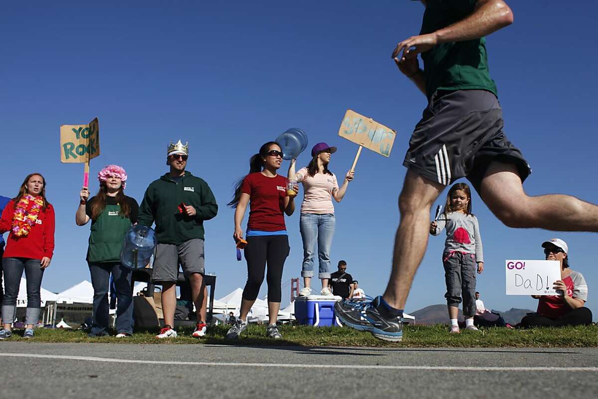 Employees of the Presidio Sports Basement cheer on runners as they make their way to the finish line during the Presidio 10k on Sunday, April 21 2013. The Presidio 10k supports the Guardsman Charity each year.