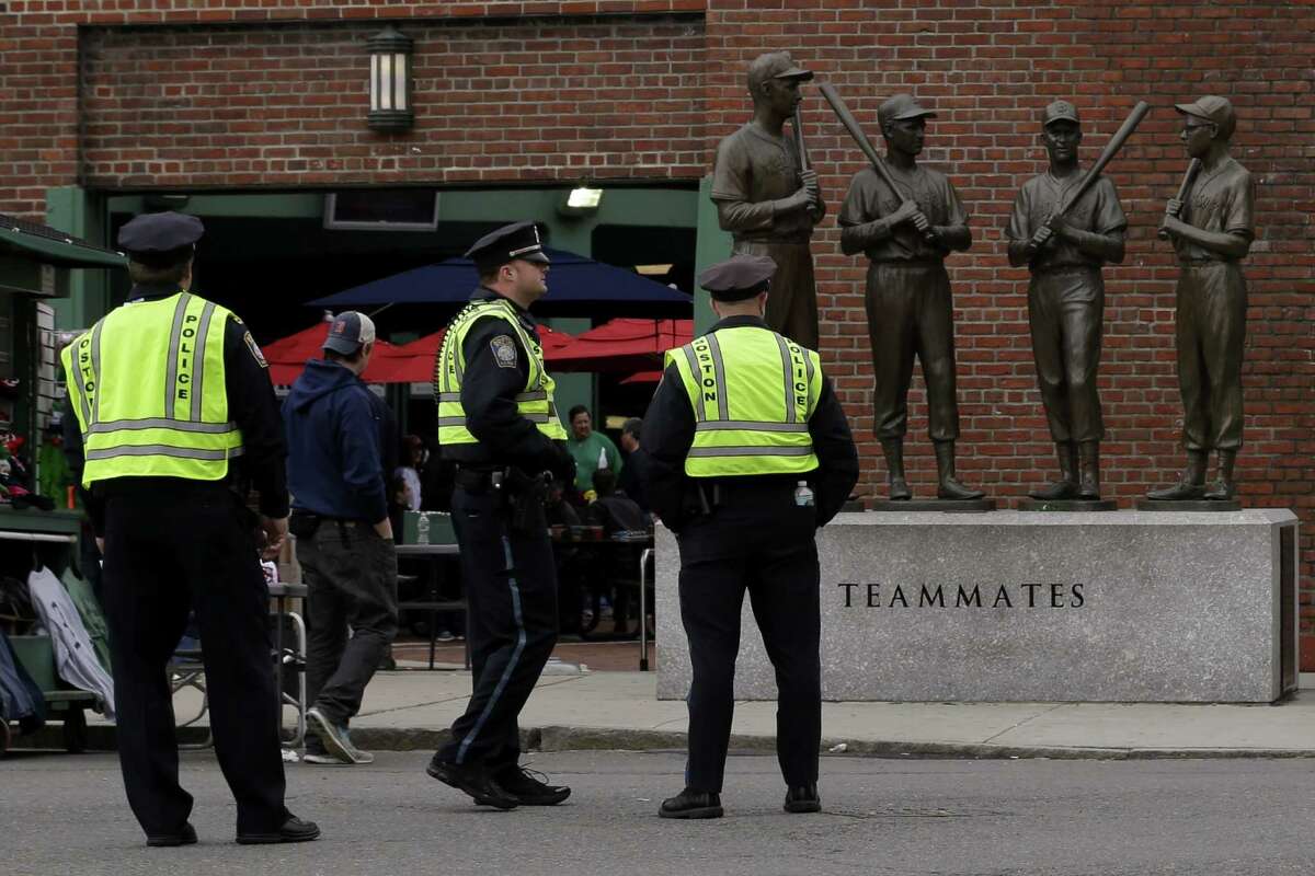 Police officers stand near statues of former Boston Red Sox greats, from left, Ted Williams, Bobby Doerr, Johnny Pesky and Dom DiMaggio during a baseball game between the Kansas City Royals and the Boston Red Sox, the first game held in the city following the Boston Marathon explosions, Saturday, April 20, 2013, in Boston. Police captured Dzhokhar Tsarnaev, 19, the surviving Boston Marathon bombing suspect, late Friday, after a wild car chase and gun battle earlier in the day left his older brother dead.