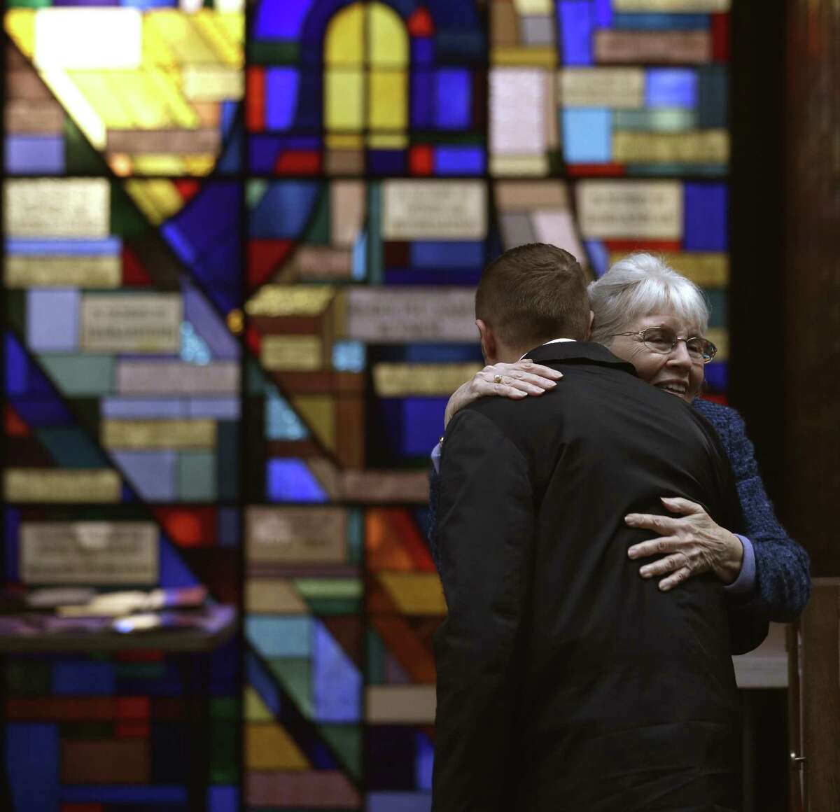Sue Haff, right, a member of Trinity Episcopal Church in Boston, greets a man arriving at Temple Israel, which allowed the Trinity congregation to hold Sunday service, Sunday, April 21, 2013, in Boston. Trinity is within the blocked-off area near the finish line of the Boston Marathon, where earlier in the week two bombs exploded.