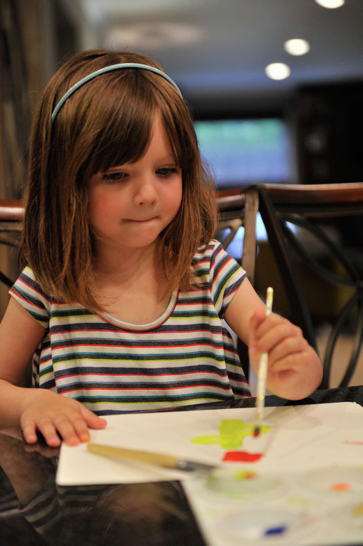 Sloane Sutherland, 5, paints in the kitchen of her home. Her mother delayed her entry into kindergarten by one year.