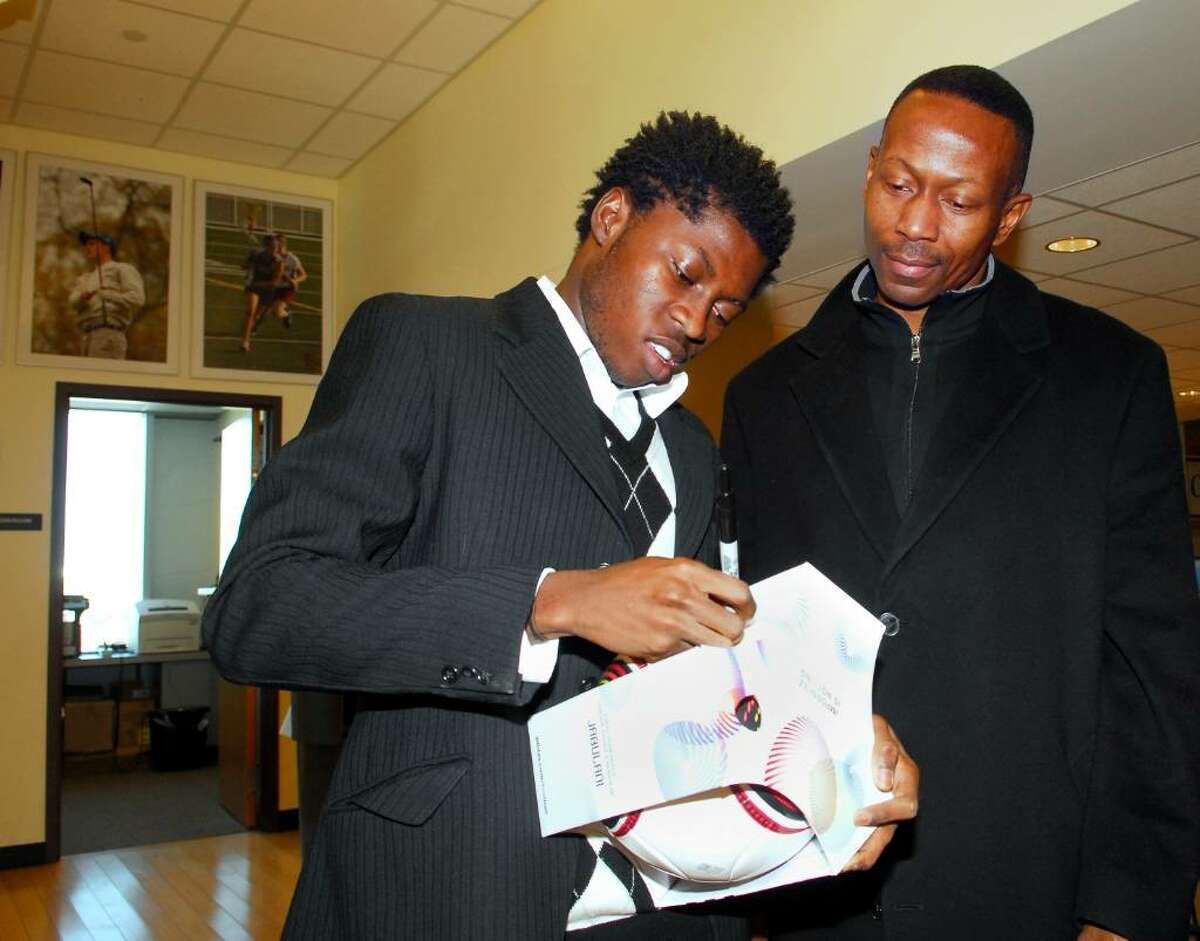 St. Luke's soccer player, Kofi Agyapong, a native of Ghana, left, signs a soccer ball for Serge Reiph (a parent of a St. Luke's student), during a ceremonial signing at St. Luke's in where it was announced that Agyapong will attend Wake Forest University in North Carolina to play soccer.