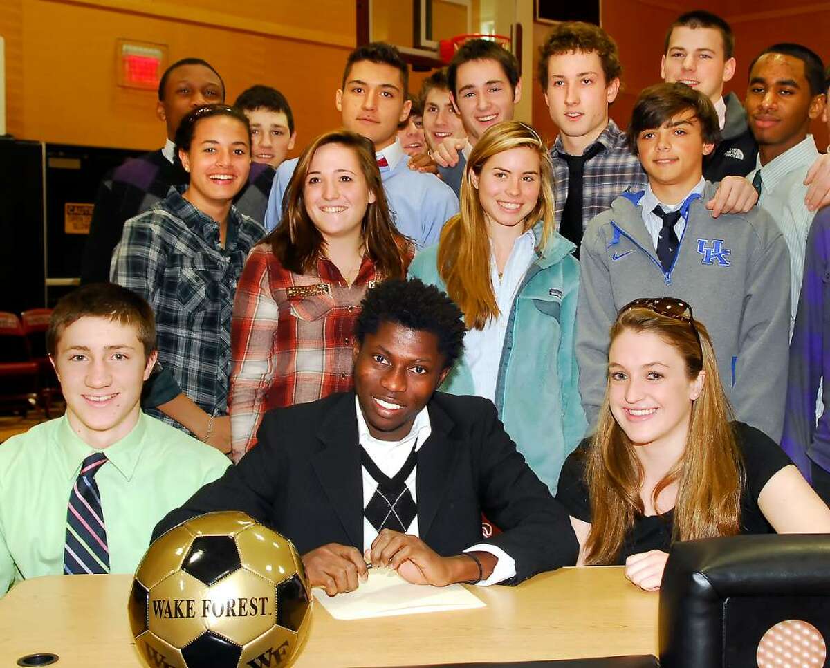 St. Luke's student and star soccer player, Kofi Agyapong, center, poses seated with his siblings, Mike Clark, left and Meghan Clark, right, and other St. Luke's classmates and friends during a signing ceremony at St. Luke's in which Agyapong's intention to attend Wake Forest University was made public.