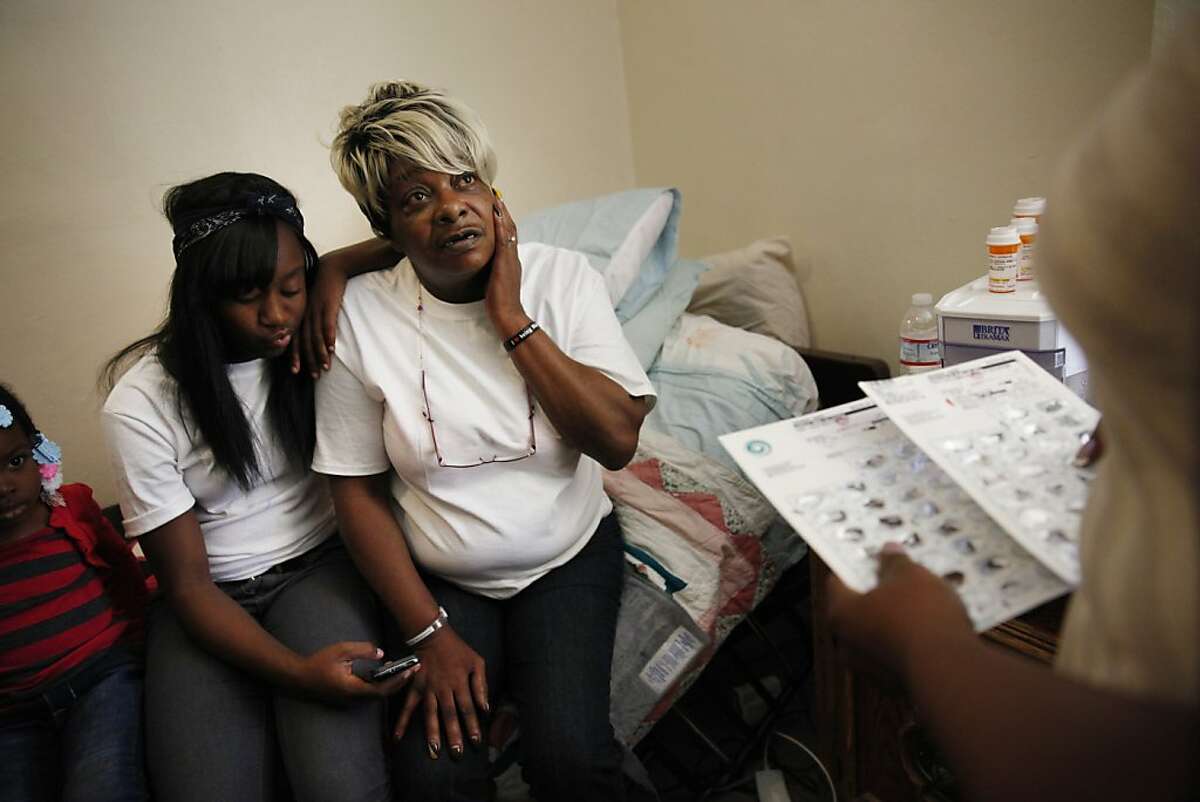 Zina Byes (right), caregiver to Harrison Hotel resident Nancy Johnson (center), discusses Johnson's medication with her as Johnson sits with her granddaughter Jasmine Wilson (left) , 13, in Johnson's room on Friday, April 12, 2013 in Oakland, Calif.