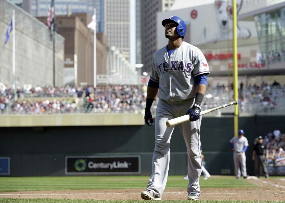 Nelson Cruz of the Rangers dejectedly returns to the dugout after being struck out by the Twins' Casey Fien in the ninth inning. Cruz went 0 for 4 in the shutout loss.
