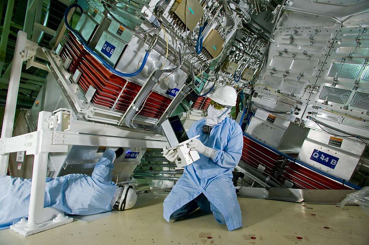 Lawrence Livermore National Laboratory technicians John Hollis (right) and Jim McElroy install a SIDE camera in the target bay of the National Ignition Facility (NIF). The camera was the last of NIF?•s 6,206 various opto-mechanical and controls system modules called ?’line replaceable units?“ or LRUs to be installed. The first LRU, a flashlamp, was installed on Sept. 26, 2001. When complete, NIF scientific experiments will demonstrate ignition and provide the platform for conducting high-energy density experiments in support of the stockpile stewardship program, fusion energy and frontier science.