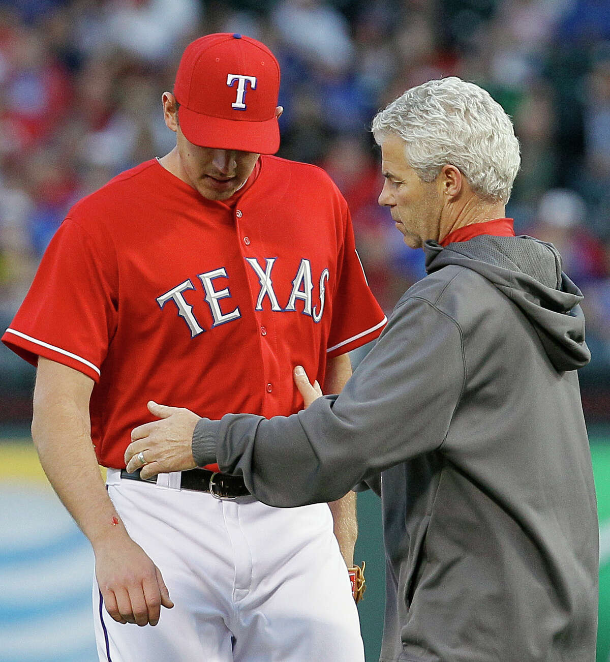 Texas Rangers trainer Jamie Reed, right, checks on starting pitcher Nick Tepesch's right forearm after being hit by a line drive in the second inning of a baseball game against the Seattle Mariners at Rangers Ballpark in Arlington, Saturday, April 20, 2013, in Arlington, Texas. Tepesch left the game. (AP Photo/Brandon Wade)