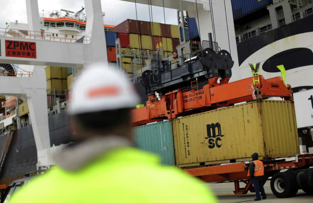 Containers are placed on a trailer after being removed from a ship at the Port of Baltimore. The government said Thursday the U.S. trade deficit narrowed in March for a second month.