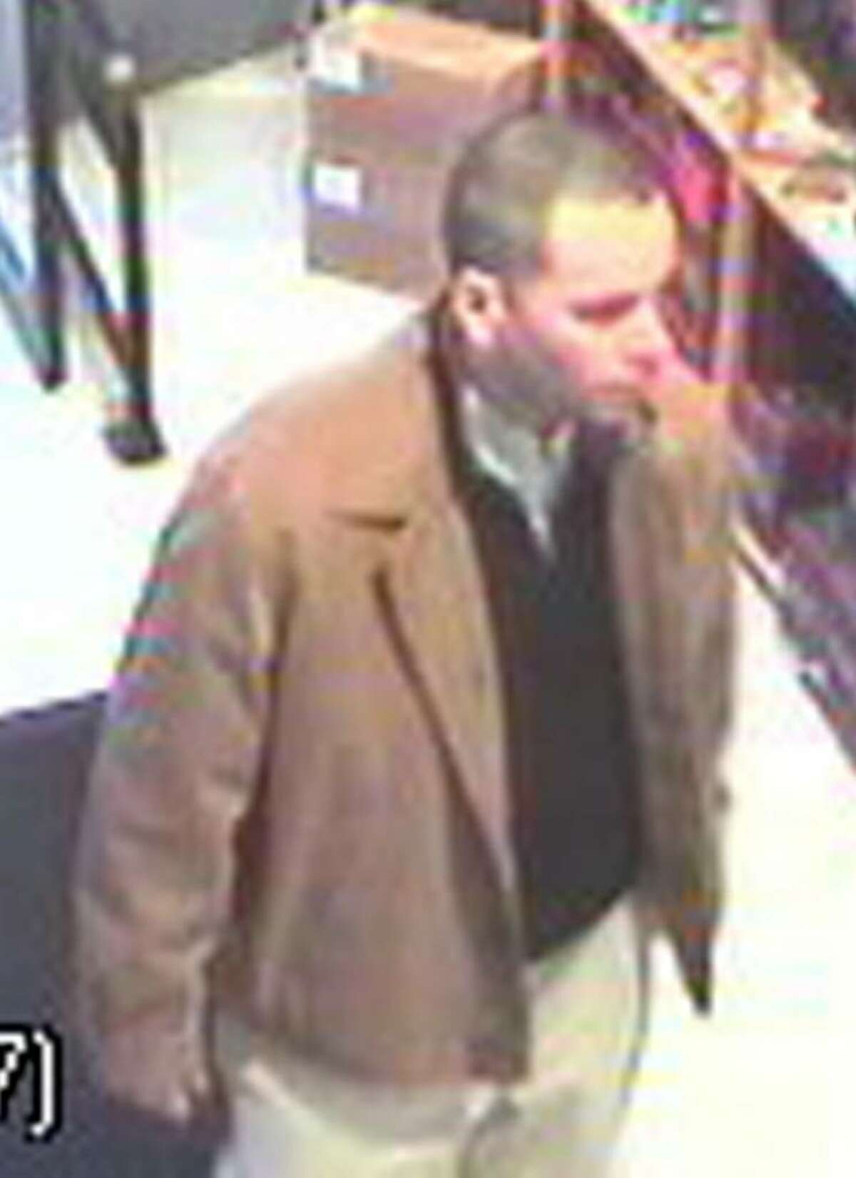 Surveillance camera images of man suspected of spending spree with stolen credit cards. The suspect is described as a white man, about 6 feet tall with a medium build and very short or thinning dark hair. He was dressed in khaki pants and a tan jacket, and wore glasses when he was in one of the stores. He was driving a newer model four-door Jeep Liberty, gold or tan in color, with a retractable roof.